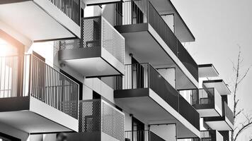 fragmento do a edifício de fachada com janelas e varandas. moderno apartamento edifícios em uma ensolarado dia. fachada do uma moderno residencial prédio. Preto e branco. foto