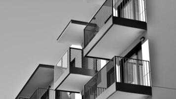 fragmento do a edifício de fachada com janelas e varandas. moderno apartamento edifícios em uma ensolarado dia. fachada do uma moderno residencial prédio. Preto e branco. foto