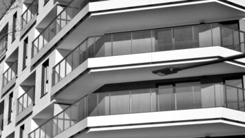 fragmento do a edifício de fachada com janelas e varandas. moderno apartamento edifícios em uma ensolarado dia. fachada do uma moderno residencial prédio. Preto e branco. foto