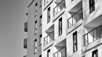 fragmento do a edifício de fachada com janelas e varandas. moderno apartamento edifícios em uma ensolarado dia. fachada do uma moderno residencial prédio. Preto e branco. foto