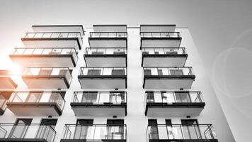 fragmento do uma fachada do uma construção com janelas e varandas. moderno apartamento edifícios em uma ensolarado dia. fachada do uma moderno apartamento prédio. Preto e branco. foto