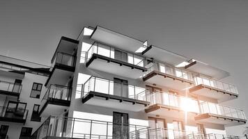 fragmento do uma fachada do uma construção com janelas e varandas. moderno apartamento edifícios em uma ensolarado dia. fachada do uma moderno apartamento prédio. Preto e branco. foto