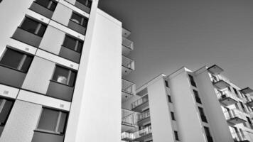 fragmento do uma fachada do uma construção com janelas e varandas. moderno apartamento edifícios em uma ensolarado dia. fachada do uma moderno apartamento prédio. Preto e branco. foto