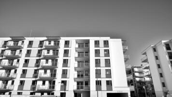 fragmento do uma fachada do uma construção com janelas e varandas. moderno apartamento edifícios em uma ensolarado dia. fachada do uma moderno apartamento prédio. Preto e branco. foto