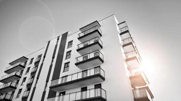 fragmento do uma fachada do uma construção com janelas e varandas. moderno apartamento edifícios em uma ensolarado dia. fachada do uma moderno apartamento prédio. Preto e branco. foto