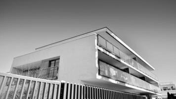 fragmento do uma fachada do uma construção com janelas e varandas. moderno apartamento edifícios em uma ensolarado dia. fachada do uma moderno apartamento prédio. Preto e branco. foto