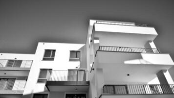fragmento do uma fachada do uma construção com janelas e varandas. moderno apartamento edifícios em uma ensolarado dia. fachada do uma moderno apartamento prédio. Preto e branco. foto