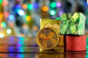 caixas de presente na mesa de madeira, decoração de natal, luzes desfocadas foto