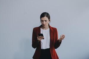 chateado jovem ásia mulher segurando Smartphone em pé em isolado branco fundo. ela estava muito estressado e depressivo. foto