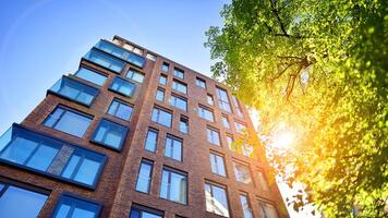 eco arquitetura. verde árvore e Novo residencial prédio. harmonia do natureza e modernidade. moderno apartamento construção com Novo apartamentos dentro uma verde residencial área. foto