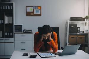 retrato do cansado jovem o negócio ásia mulher trabalhos com documentos imposto computador portátil computador dentro escritório. triste, infeliz, preocupado, depressão, ou empregado vida estresse conceito foto