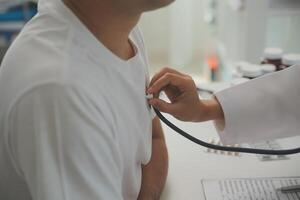 jovem médico é usando uma estetoscópio ouço para a batimento cardiaco do a paciente. tiro do uma fêmea médico dando uma masculino paciente uma Verifica acima foto