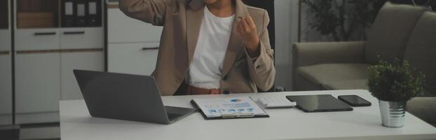 jovem feliz empresária usando computador dentro moderno escritório com colegas. à moda lindo Gerente sorridente, trabalhando em financeiro e marketing projetos. bebendo chá ou café a partir de uma caneca. foto