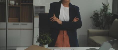 jovem feliz empresária usando computador dentro moderno escritório com colegas. à moda lindo Gerente sorridente, trabalhando em financeiro e marketing projetos. bebendo chá ou café a partir de uma caneca. foto