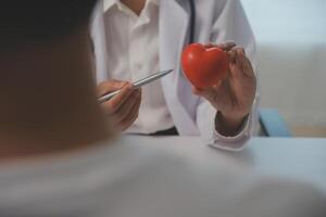 mãos do médico mulher segurando vermelho coração, mostrando símbolo do amor, humano Apoio, suporte para paciente, promovendo médico seguro, cedo checar para assistência médica, cardiologista ajuda. fechar acima do objeto foto