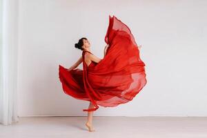 dançarino dentro uma vermelho vôo vestir. mulher bailarina dançando em uma branco estúdio fundo foto