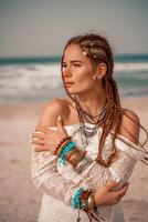 modelo dentro boho estilo dentro uma branco grandes vestir e prata joalheria em a de praia. dela cabelo é trançado, e lá estão muitos pulseiras em dela braços. foto