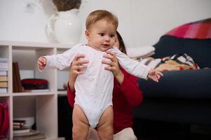 adorável bebê Garoto dentro branco maiô, dentro a mãos do dele amoroso carinhoso irmã jogando com ele às lar. pessoas. infância. infância. infância. crianças Educação WL desenvolvimento. a conceito do feliz família foto