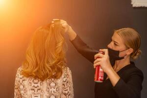 mulheres salão Penteado. cabeleireiro usa spray de cabelo em do cliente cabelo dentro salão, retrato do dois lindo mulheres foto