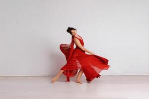 dançarino dentro uma vermelho vôo vestir. mulher bailarina dançando em uma branco estúdio fundo foto