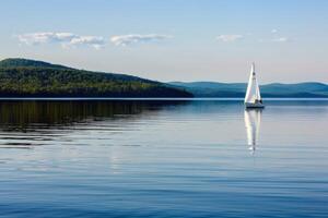barco a vela à deriva preguiçosamente em calma lago, Está velas ondulante dentro a □ Gentil verão brisa foto
