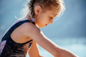 uma jovem menina é sentado em a praia, olhando às a água foto