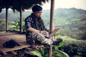 jovem asiático freelance homem usa laptop trabalhando sobre viagens de editor ou blogueiro em doi ang khang 2000 chá verde fazenda chiang mai tailândia. foto