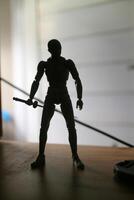 sombra silhueta do uma plástico brinquedo segurando uma espada foto