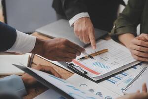 co conferência de trabalho, reunião da equipe de negócios presente, colegas investidores discutindo os dados do gráfico financeiro do novo plano na mesa do escritório com laptop e tablet digital, finanças, contabilidade, investimento. foto