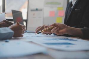 co conferência de trabalho, reunião da equipe de negócios presente, colegas investidores discutindo os dados do gráfico financeiro do novo plano na mesa do escritório com laptop e tablet digital, finanças, contabilidade, investimento. foto