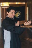 uma homem praticando a fundamental asa chun técnica conhecido Como bronzeado são dentro uma marcial artes estúdio. foto