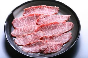 cru carne fatia para churrasco japonês estilo, yakiniku. carnes estão ser cozinhou em a fogão dentro uma japonês restaurante foto