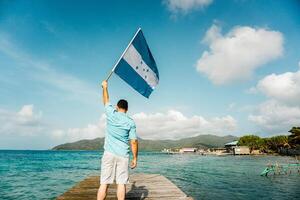 homem segurando uma Honduras bandeira em guanjá porta. foto