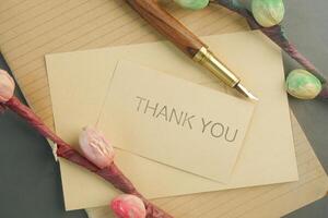mensagem de agradecimento e envelope na mesa de madeira foto