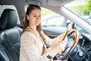 jovem mulher dirigindo uma carro e usando Smartphone inscrição para Visão uma mapa mostrando viagem rota foto