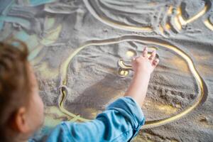 pequeno menina desenhando com seus dedos em a interativo areia mesa. Treinamento mestre aula. Alto qualidade foto