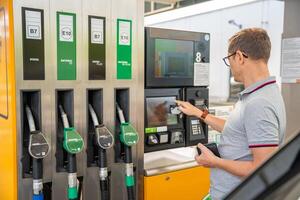 a homem paga para combustível com uma crédito cartão em terminal do self-service o preenchimento estação dentro Europa foto