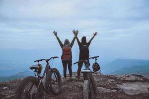 Amantes asiáticos mulheres e homens viajam pela natureza. viajar relaxar andar em um deserto de bicicleta em estado selvagem. de pé em um penhasco rochoso. Tailândia foto