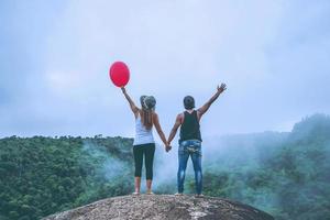 amantes, mulheres e homens asiáticos viajam relaxam no feriado. ficar em um penhasco rochoso. madeira da natureza selvagem na montanha. foto