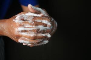 jovem homem lavando mãos com Sabonete caloroso água isolado em Preto fundo foto