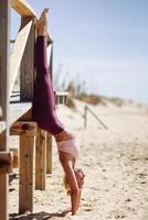 mulher loira caucasiana praticando ioga na praia