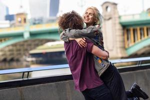 casal feliz se abraçando perto da ponte Southwark sobre o rio Tamisa, em Londres