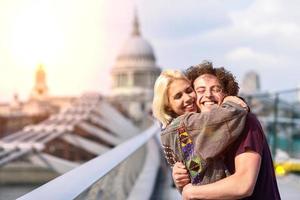 casal feliz abraçando a ponte do milênio, rio Tamisa, em Londres. foto
