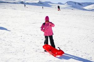 menina andando de trenó na estância de esqui de sierra nevada. foto