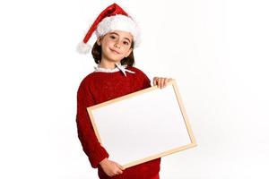 menina com chapéu de Papai Noel segurando um quadro em branco foto