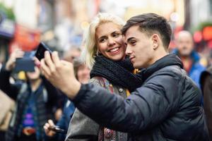 casal feliz de turistas tomando selfie em uma rua movimentada.