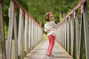 menina bonitinha se divertindo em uma ponte rural foto