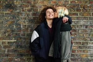 jovem casal curtindo a cidade de Camden em frente a uma parede de tijolos típica de Londres foto