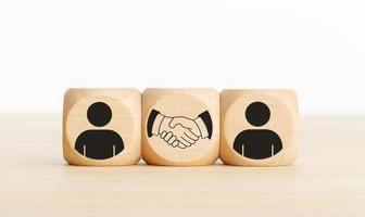 acordo, parceria ou conceito de negócio. pessoas e ícones de aperto de mão em blocos de madeira. copie o espaço foto