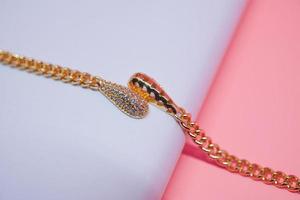 foto de uma pulseira de menina com um motivo de pêndulo pervertido em um fundo rosa